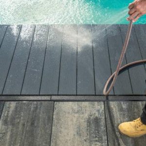 Men Pressure Washing Outdoor Swimming Pool Composite Deck. Pool Surrounding Maintenance Theme.